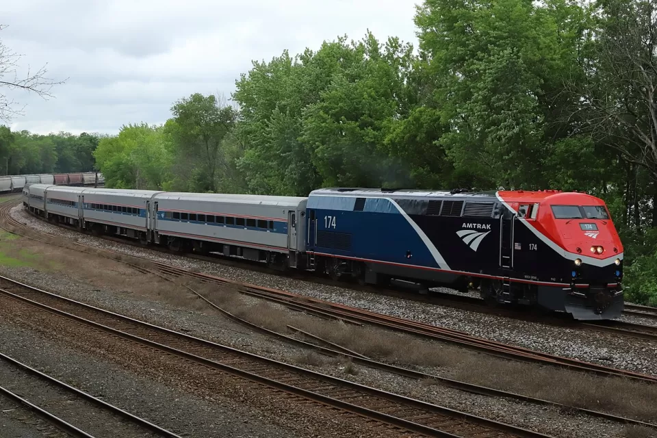 Amtrak Borealis train passing by green forest in Hastings, Minnesota.